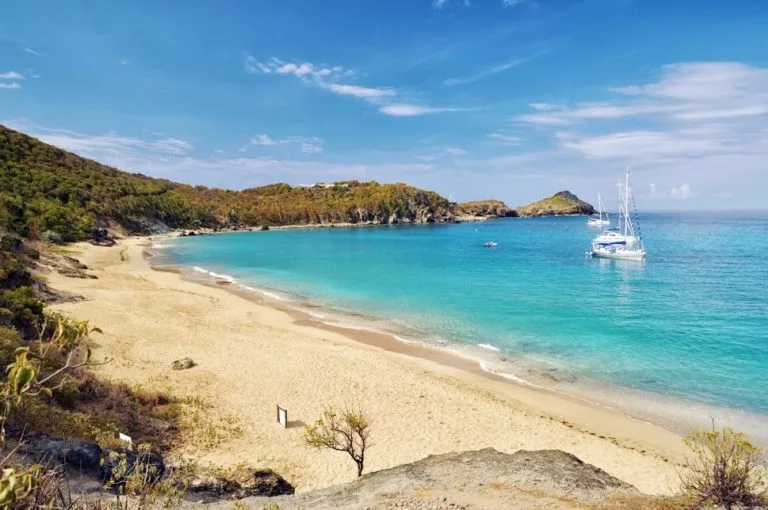 St. Barths Colombier beach with blue water and sail boats anchored. 